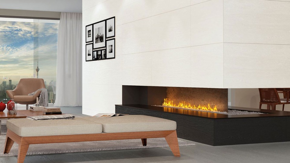 Aqui foi utilizado o porcelanato Woodstok BK, também no detalhe da lareira. O contraste da peça, que simula a madeira escura, com a predominância de cores claras no ambiente, transmitiu harmonia para o espaço.
